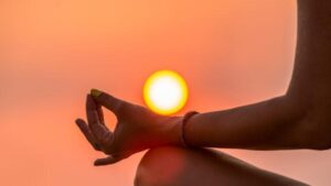 dita pizzicate in una meditazione con il sole sullo sfondo
