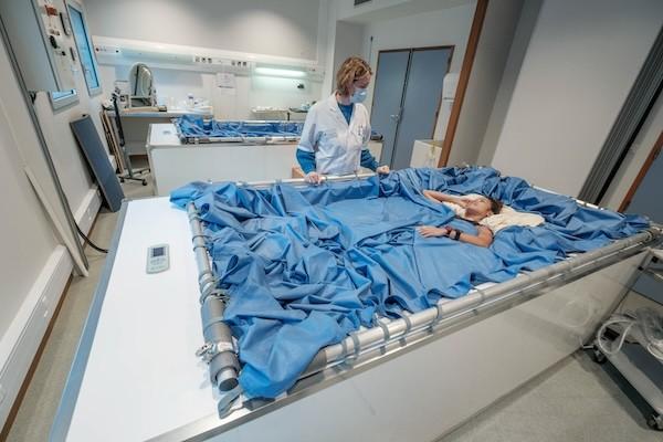 Un medico in piedi accanto a un paziente in un grande letto