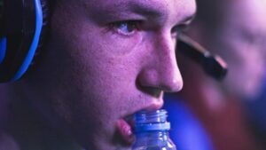 Primo piano di un gamer maschio concentrato che succhia una bottiglia di plastica e guarda il replay