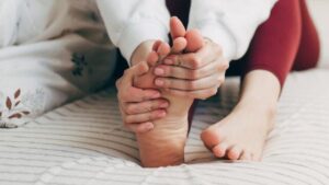 Giovane donna con piedi piatti che fa massaggio
