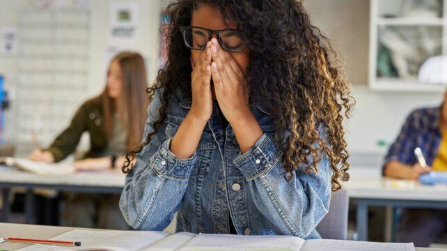 Giovane adulto stanco seduto a una scrivania in un'aula