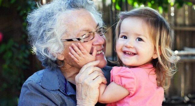 Una donna anziana abbraccia un bambino mentre entrambi sorridono