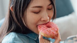 donna che mangia una ciambella rosa