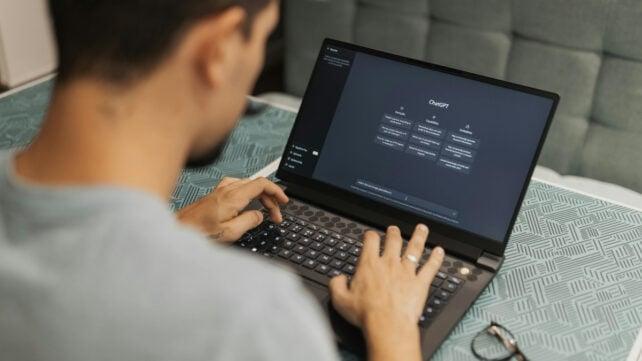 Vista dall'alto di un uomo che digita su un laptop, utilizzando un chatbot AI