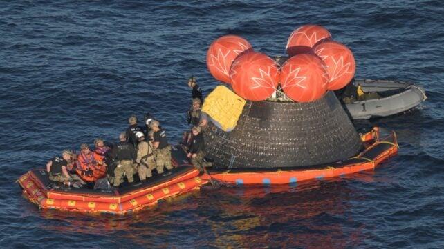 Astronauti e equipaggio di supporto su una zattera dopo l'ammaraggio della navetta spaziale Orion