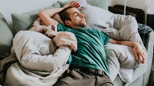 Uomo seduto sul divano in una posizione scomoda