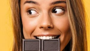 Una giovane donna bionda che morde del cioccolato fondente