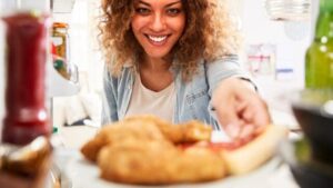 Vista dall'interno di un frigorifero, di una giovane donna che si allunga per prendere la pizza avanzata