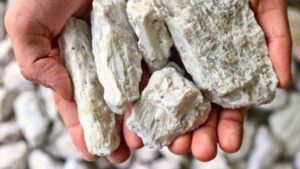 Mani che tengono pezzi di roccia minerale contenente litio, illustrando un vasto deposito di litio non sfruttato identificato sotto le Montagne Appalache.