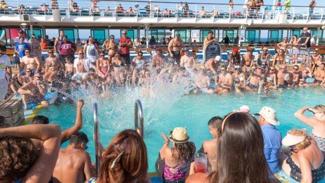 Folla di passeggeri riuniti attorno a una piscina sul ponte di una nave da crociera
