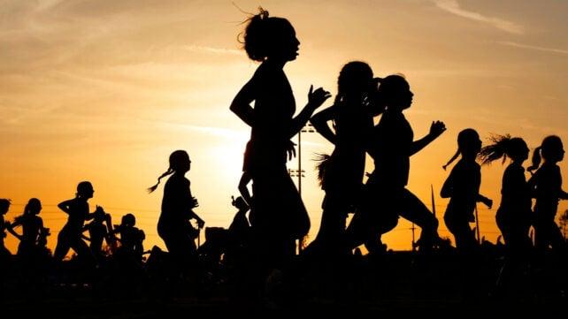 Silhouette di molte persone che corrono al tramonto