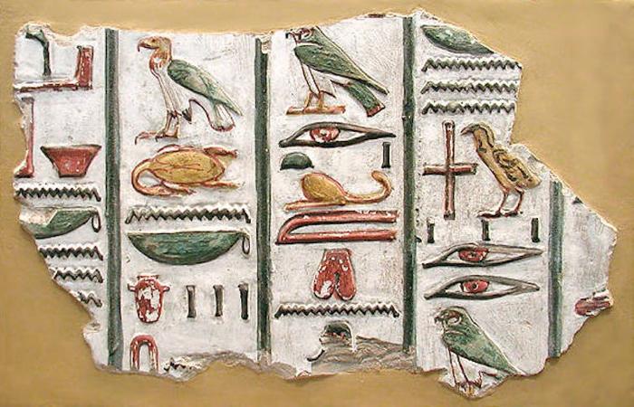 Geroglifici egiziani che raffigurano uccelli, occhi e altre immagini in verde, rosso e oro.