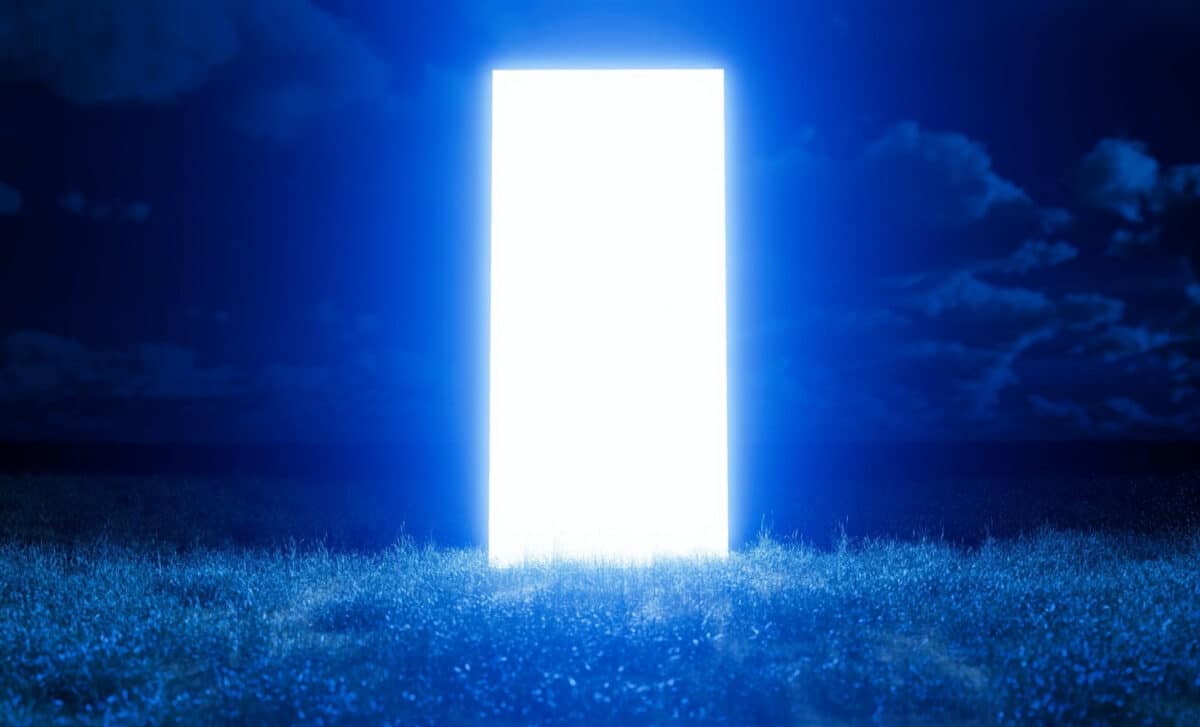 a-shimmering-rectangular-doorway-floating-in-a-field-of-grass-at-night-with-a-blue-sky-and-clouds-in-the-background-scaled-1.jpg