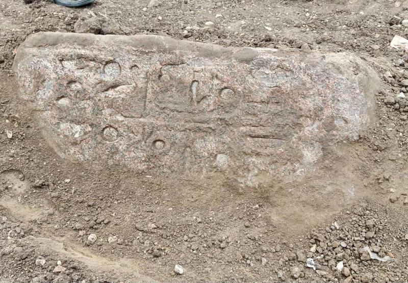 None Un blocco di granito con geroglifici egizi, immerso nella terra.