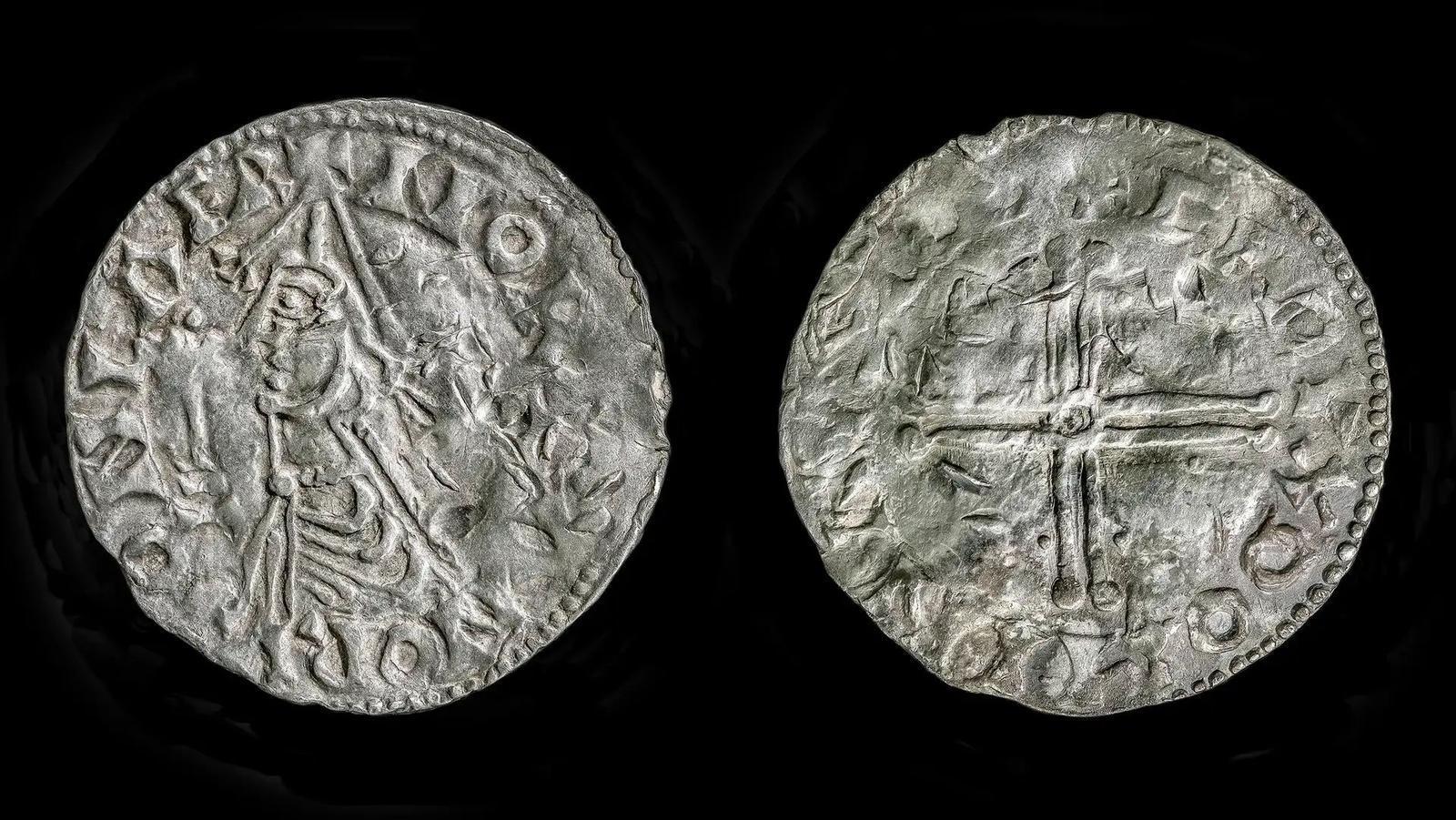 Primo piano del recto e del verso di una moneta d’argento; su un lato è raffigurato il profilo di un uomo e sull’altro una croce.