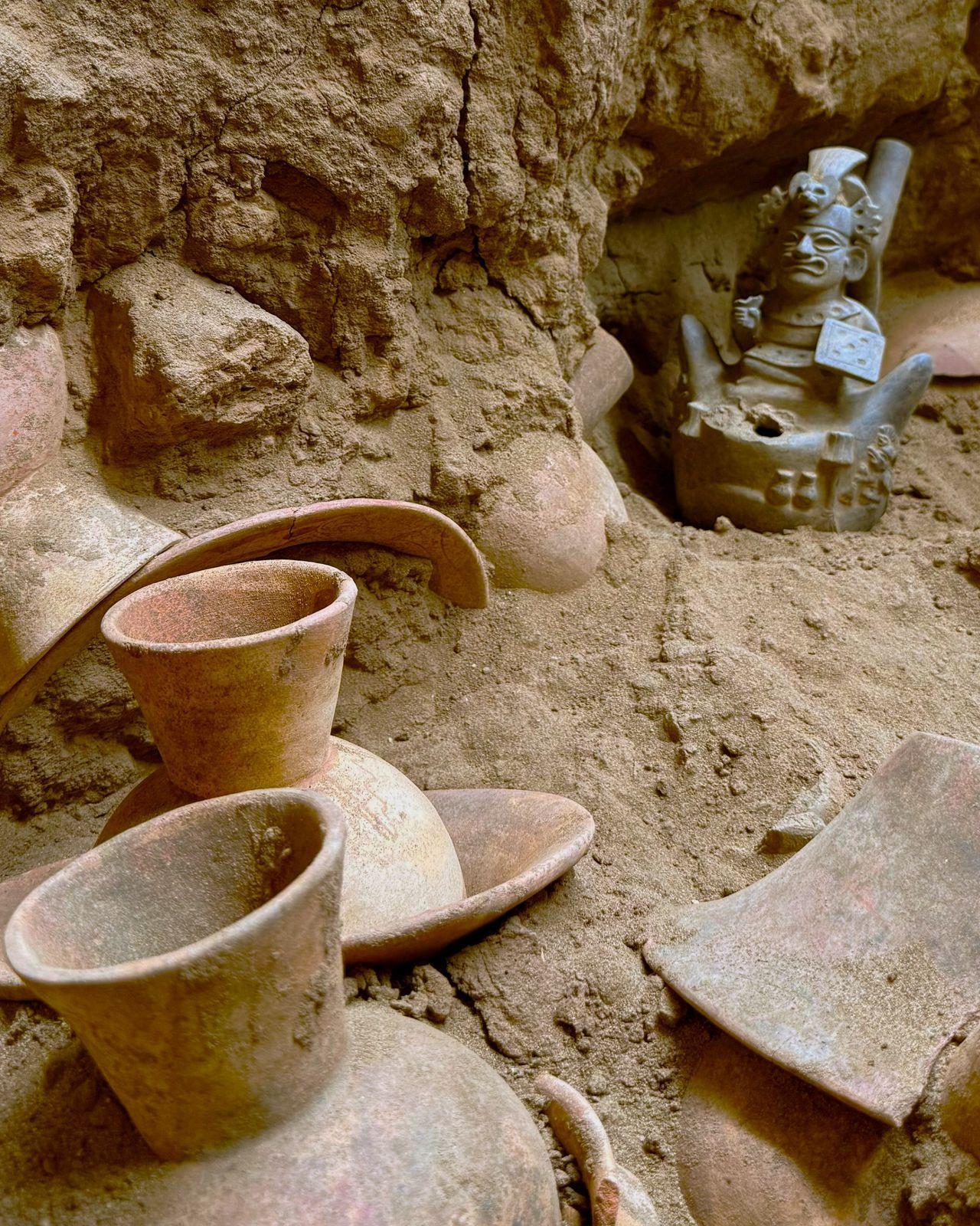 Una serie di ciotole e vasi in ceramica è parzialmente dissotterrata in una grotta.