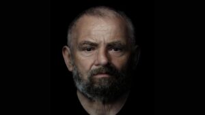 Foto di un uomo calvo con la barba grigia su sfondo nero