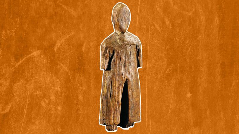 una statuetta umana di legno su sfondo arancione