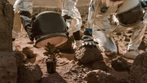 Astronauti che cercano di proteggere una pianta in un terreno simile a quello di Marte.